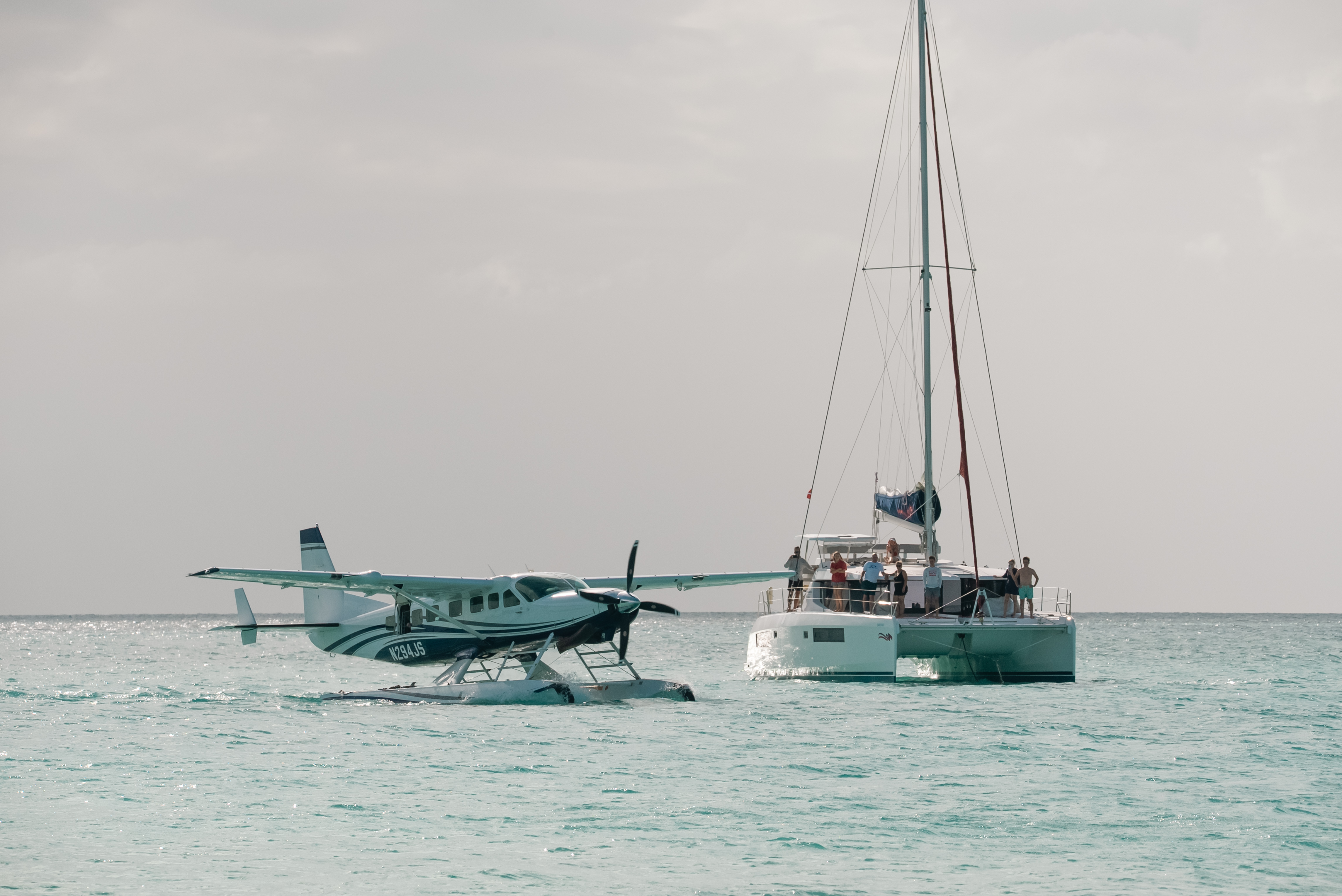 A flyExclusive amphibious Grand Caravan on the water beside a catamaran