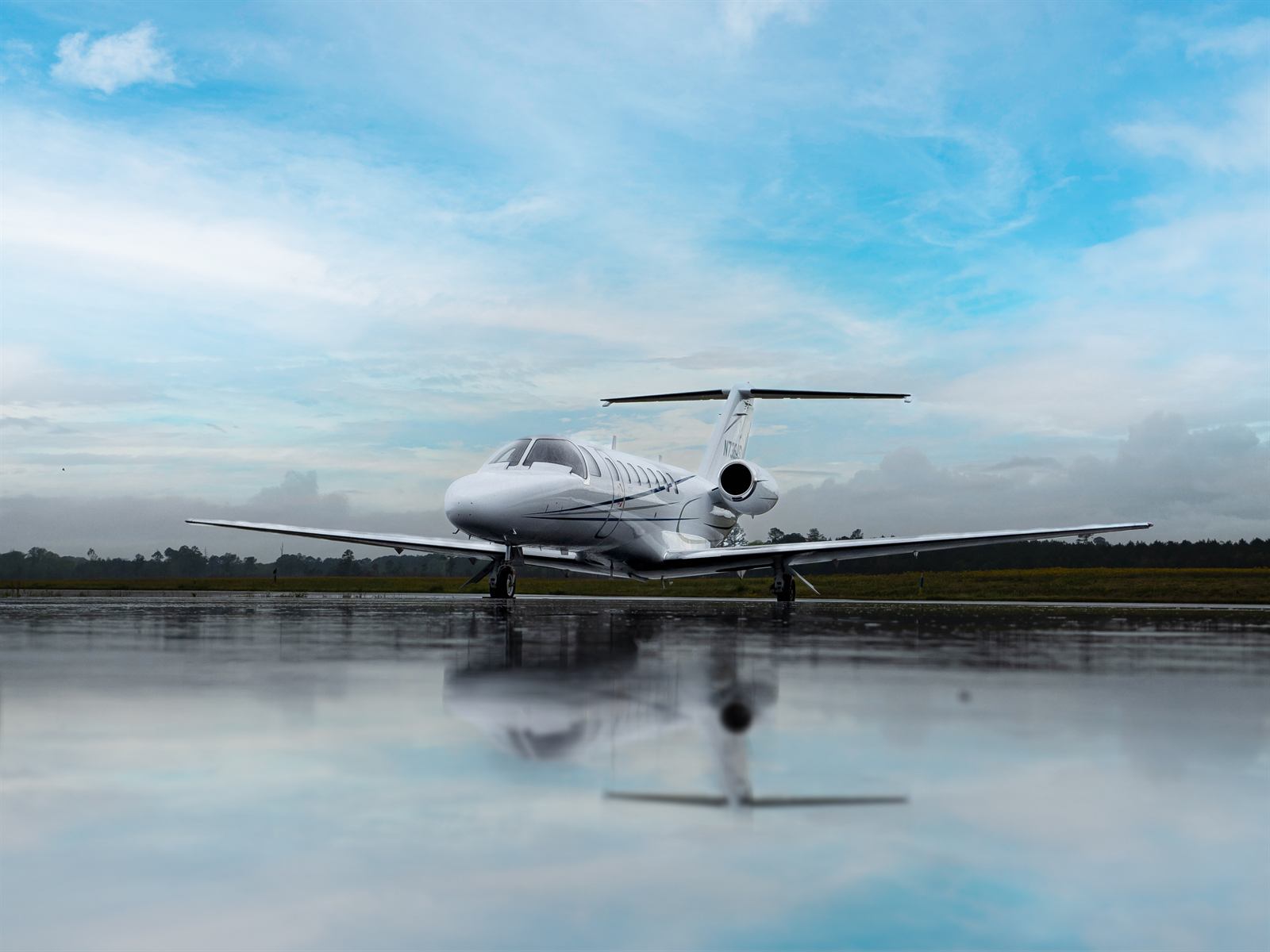 A flyExclusive Citation CJ3+ on a wet ramp at dusk, reflected in the standing water