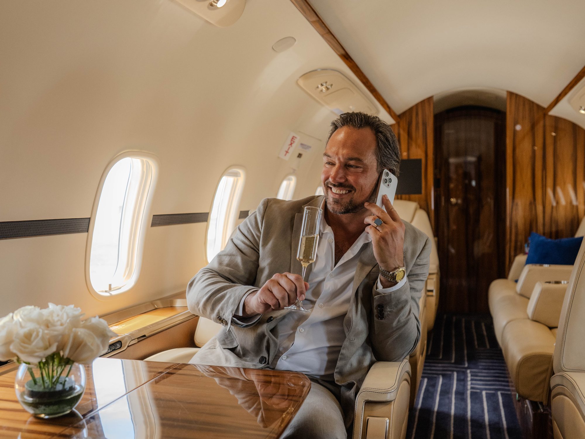 An owner taking a call with a glass of champagne in the cabin of a flyExclusive jet