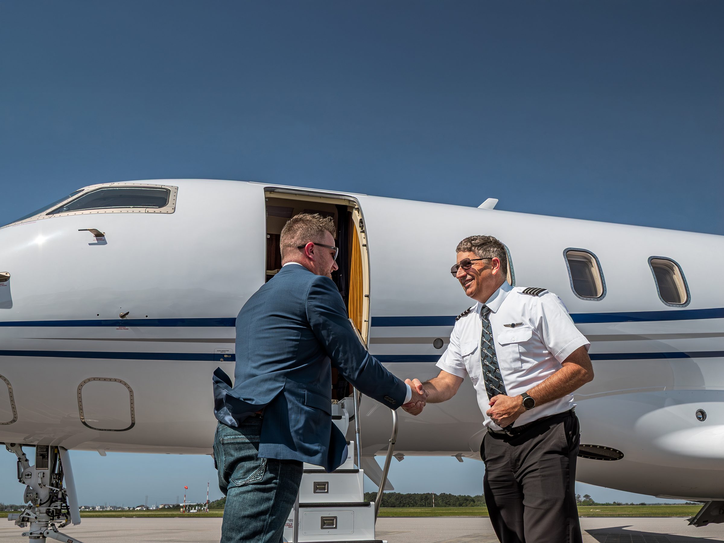 A flyExclusive captain shaking hands with a passenger at the airstairs of a Challenger 350