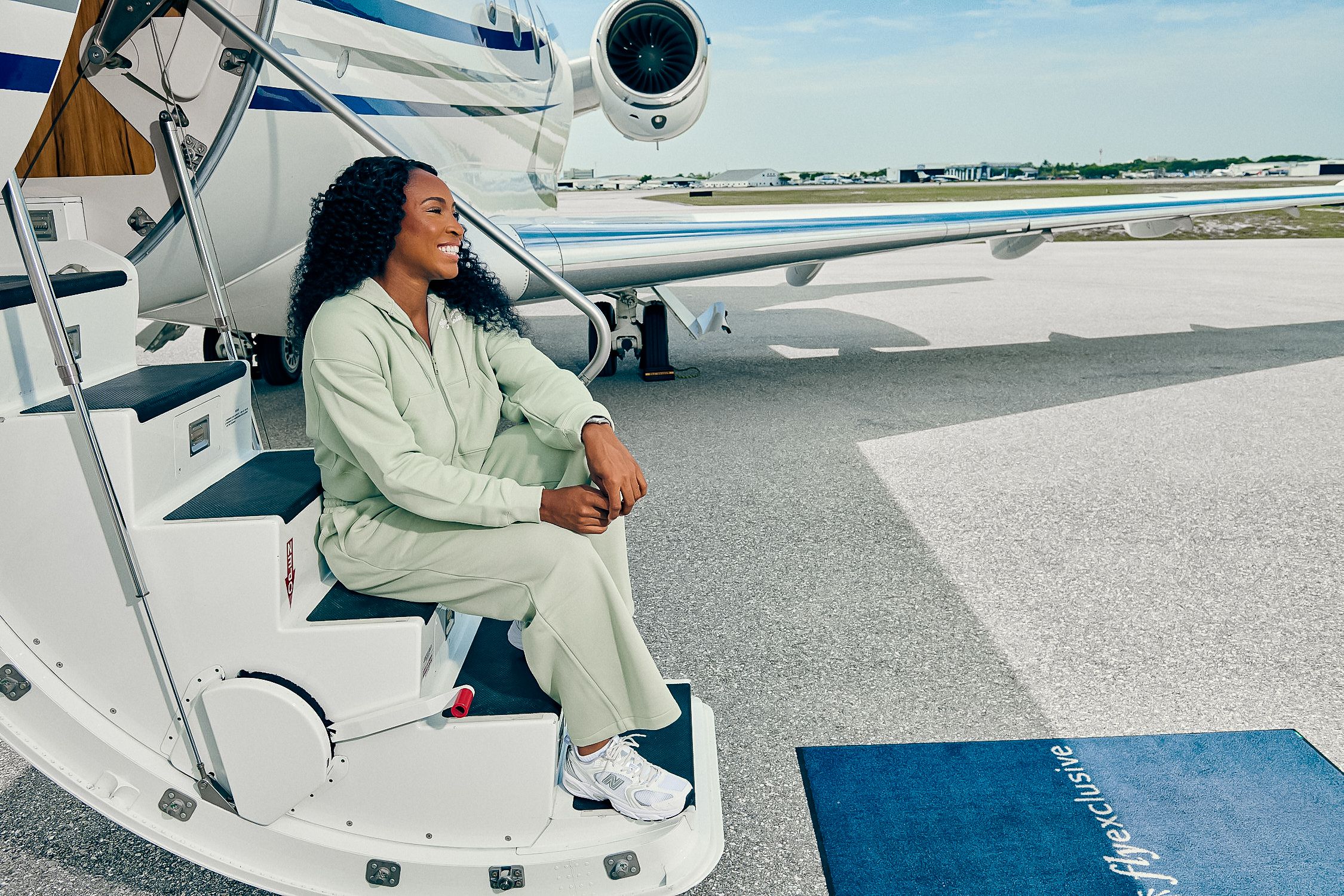 Coco Gauff seated on the airstairs of a flyExclusive private jet