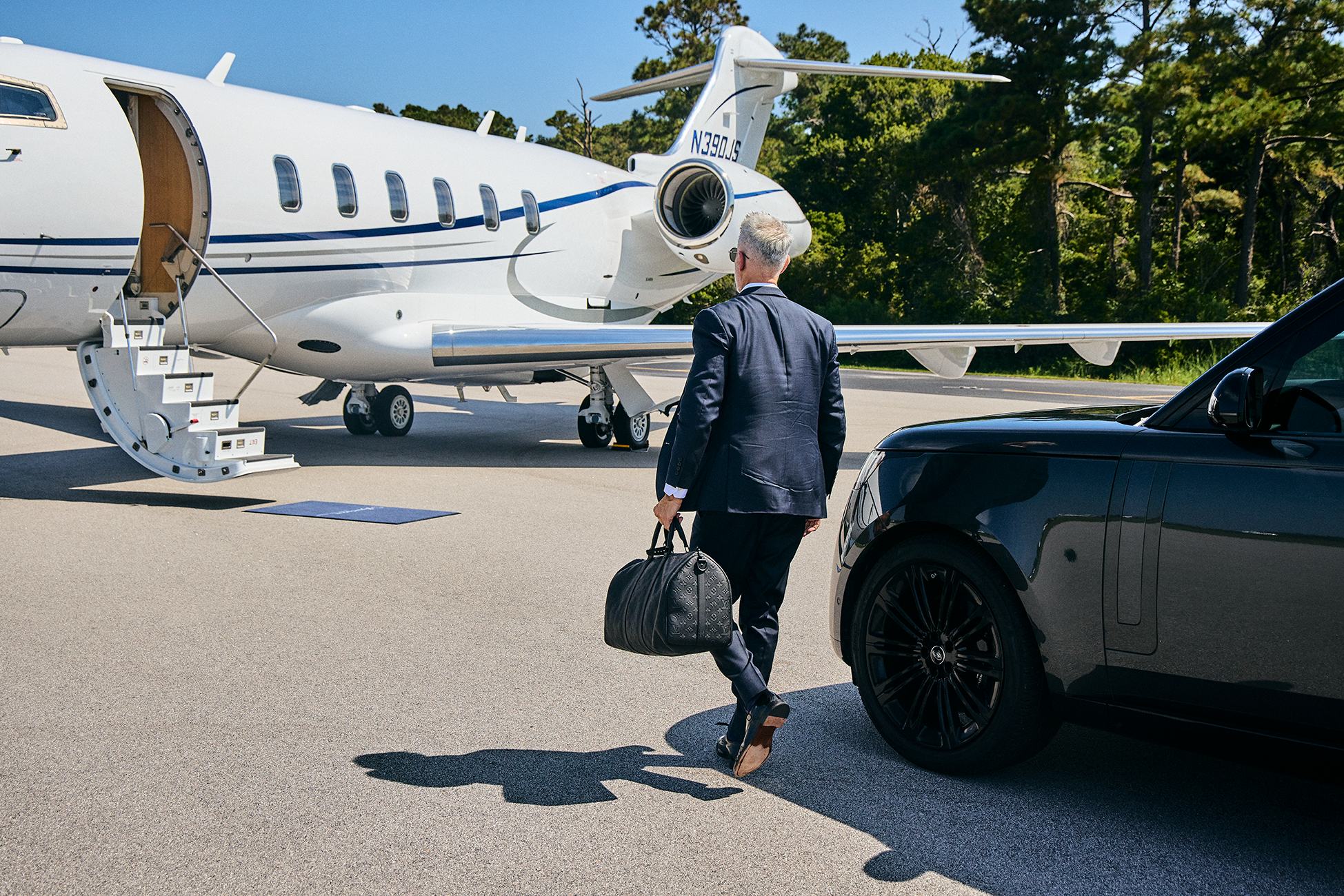 A flyExclusive member walking from an SUV to a waiting Challenger 350